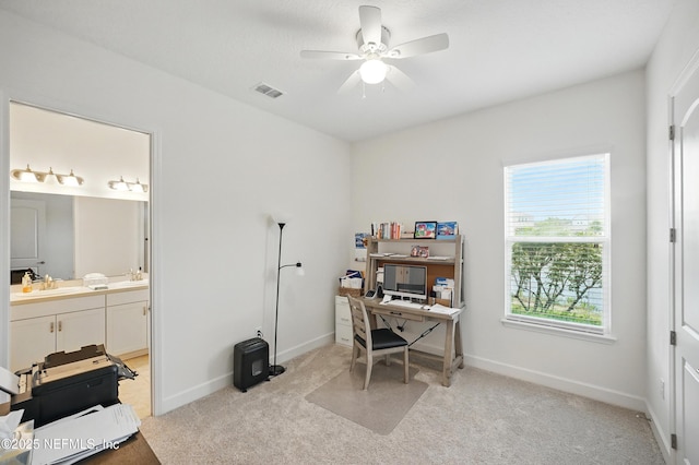 office area featuring visible vents, a sink, light carpet, baseboards, and a ceiling fan