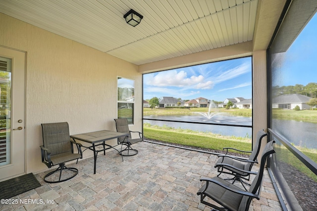sunroom / solarium featuring a water view and a residential view
