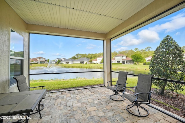 sunroom / solarium featuring a water view and a residential view