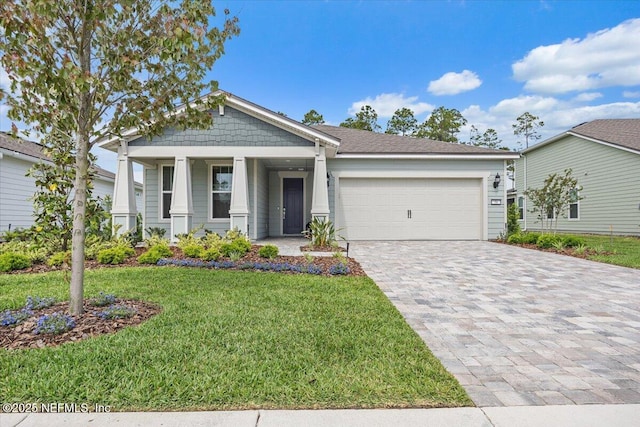 view of front of house with a front yard, decorative driveway, an attached garage, and covered porch