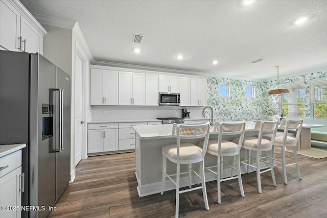 kitchen featuring dark wood-style floors, light countertops, appliances with stainless steel finishes, and crown molding