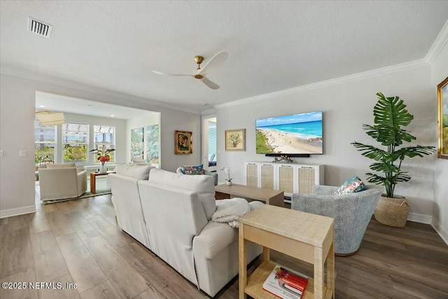 living room featuring visible vents, crown molding, a ceiling fan, and light wood-style floors