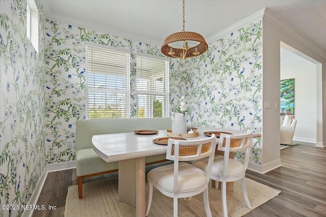 dining room with breakfast area, ornamental molding, and wallpapered walls