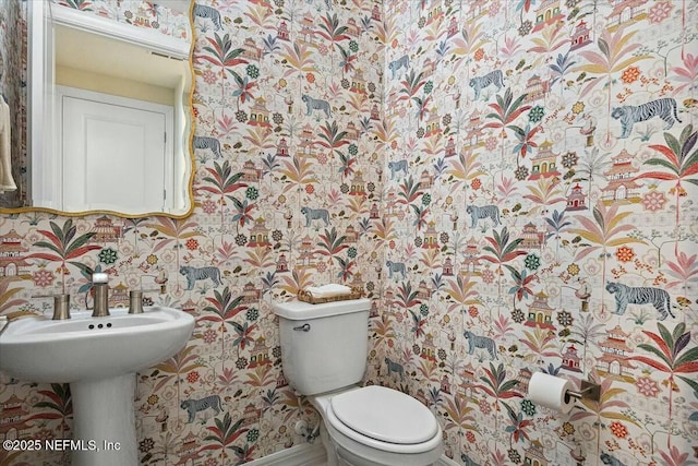 bathroom with baseboards, wallpapered walls, and toilet