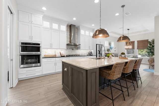 31 Tesoro Ter, Saint Augustine, FL 32095 - kitchen featuring stainless steel double oven, light wood-type flooring, gas stovetop, a sink, and wall chimney exhaust hood
