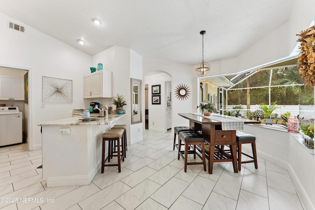 dining area with arched walkways, visible vents, and washer / dryer