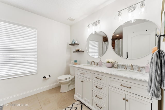 bathroom featuring double vanity, visible vents, baseboards, and a sink