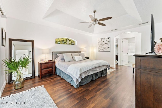 bedroom with visible vents, baseboards, a raised ceiling, and dark wood-type flooring
