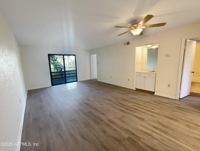 unfurnished living room featuring a sink, visible vents, baseboards, wood finished floors, and a ceiling fan