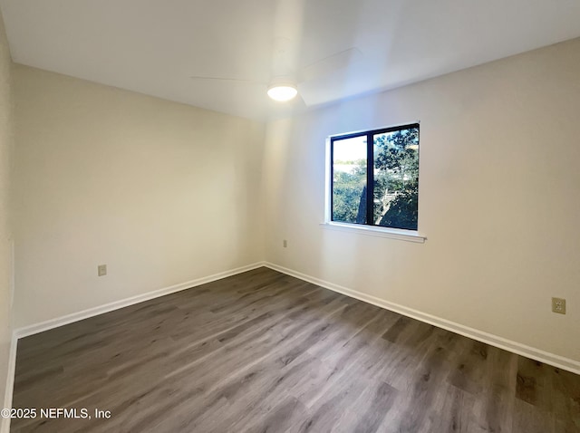 empty room featuring dark wood-style floors, a ceiling fan, and baseboards