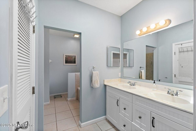 bathroom featuring baseboards, a sink, tile patterned flooring, and a closet