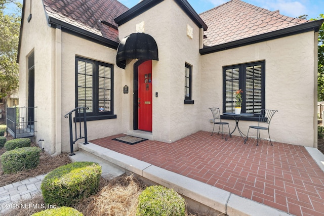 view of exterior entry with stucco siding and a high end roof
