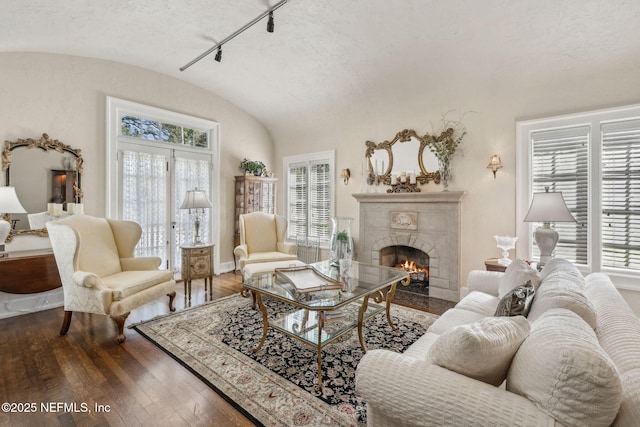 living room featuring baseboards, vaulted ceiling, hardwood / wood-style flooring, and a fireplace