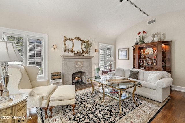 living area featuring visible vents, dark wood-style floors, a tiled fireplace, and plenty of natural light