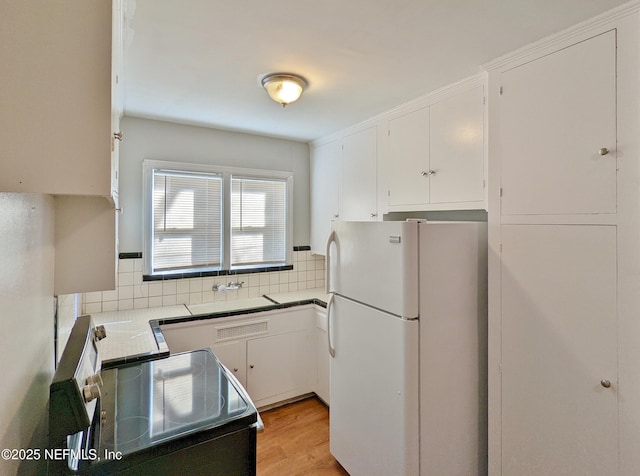 2636 Post St, Jacksonville, FL 32204 - kitchen with white cabinetry, freestanding refrigerator, decorative backsplash, and range with electric cooktop
