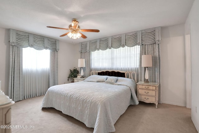 bedroom with a ceiling fan, multiple windows, and carpet flooring