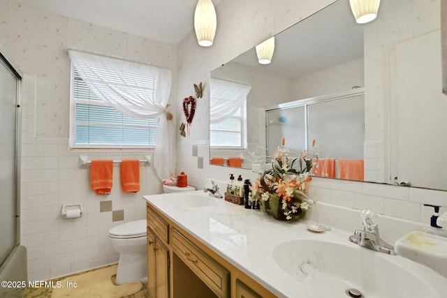 bathroom featuring double vanity, tile walls, an enclosed shower, and a sink