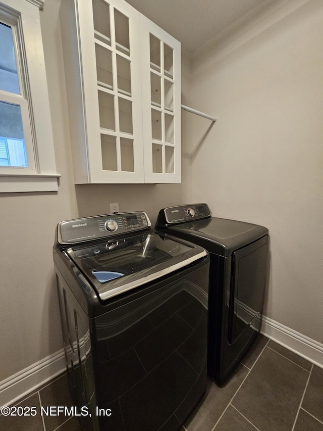 washroom with baseboards, dark tile patterned floors, laundry area, and washer and clothes dryer