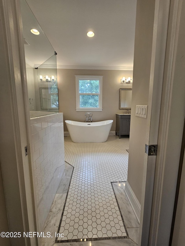 bathroom with a freestanding bath, ornamental molding, baseboards, and vanity
