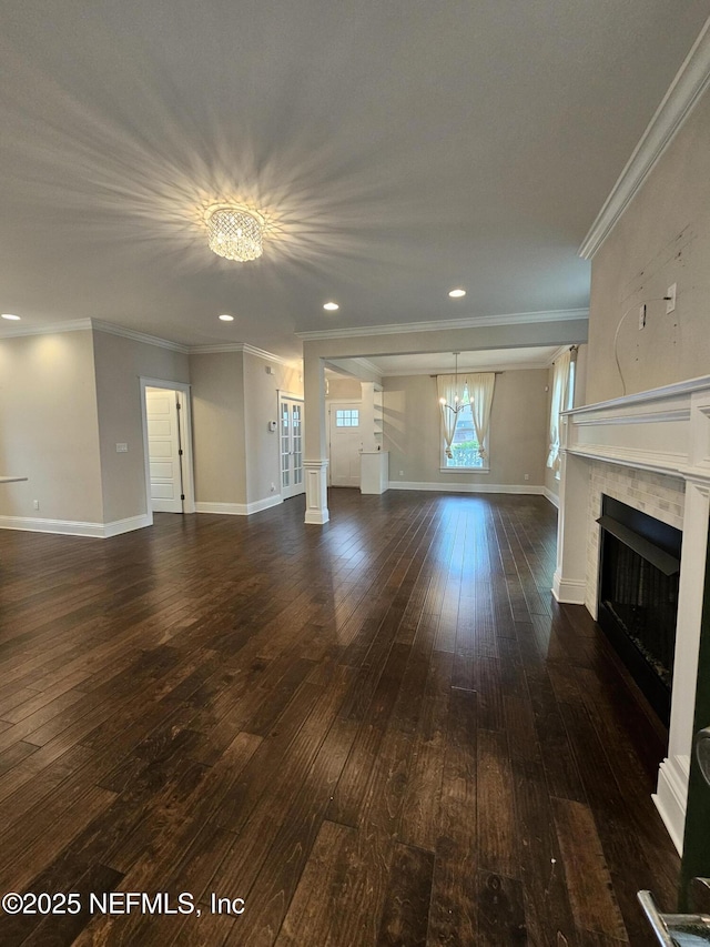 unfurnished living room with crown molding, a fireplace, dark wood-style floors, and a notable chandelier