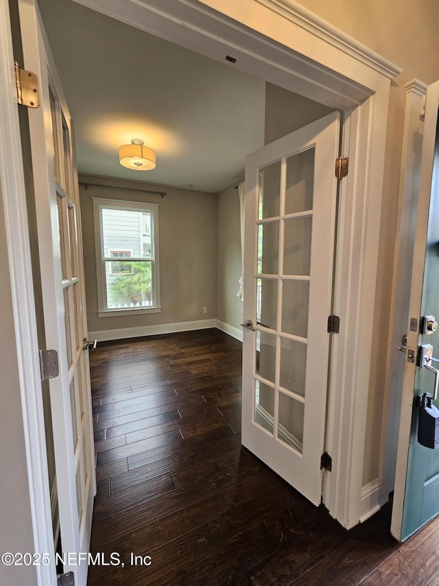 empty room featuring dark wood-style flooring, baseboards, and french doors