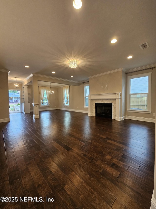 unfurnished living room with a notable chandelier, ornamental molding, a tiled fireplace, visible vents, and dark wood-style floors
