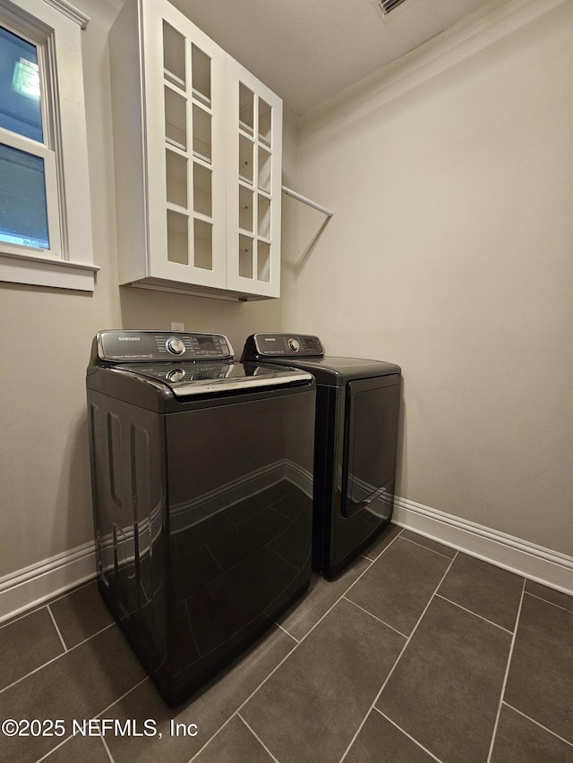 clothes washing area featuring washing machine and clothes dryer, dark tile patterned flooring, baseboards, and laundry area