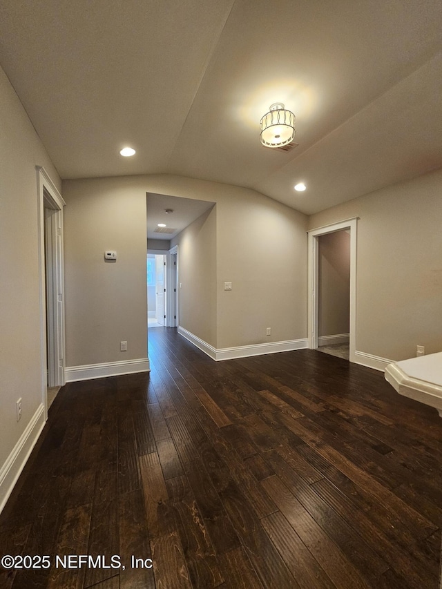 empty room featuring lofted ceiling, wood-type flooring, baseboards, and recessed lighting