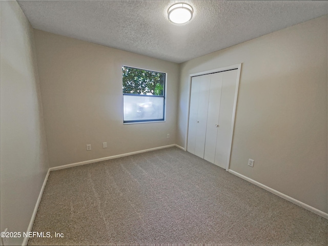 unfurnished bedroom featuring a textured ceiling, a closet, carpet floors, and baseboards