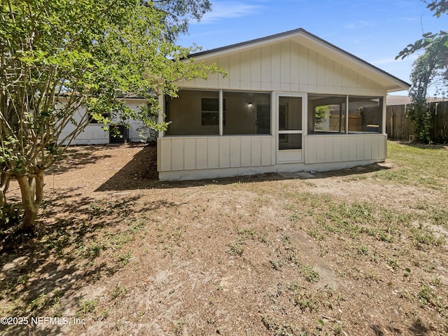 view of property exterior with a sunroom and fence