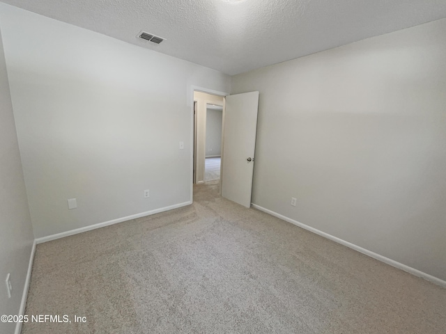 unfurnished room with baseboards, visible vents, a textured ceiling, and carpet