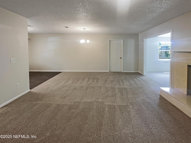 spare room with baseboards, a notable chandelier, carpet floors, and a textured ceiling