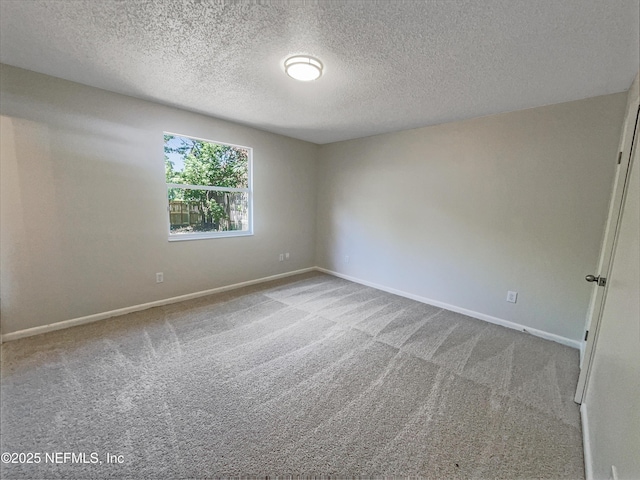 carpeted empty room with a textured ceiling and baseboards