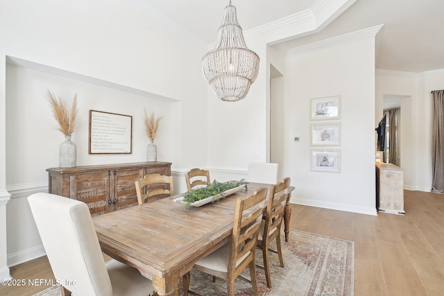 dining room with a chandelier, ornamental molding, light wood-type flooring, and baseboards