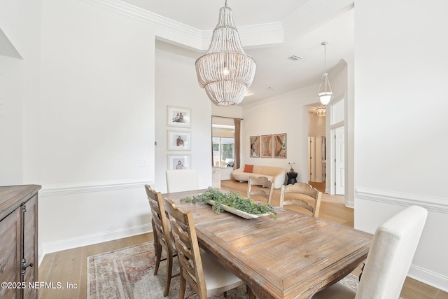 dining room featuring a chandelier, light wood-type flooring, crown molding, and baseboards