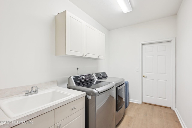 laundry room featuring washer and dryer, cabinet space, light wood-type flooring, and baseboards