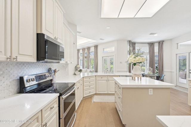 kitchen with stainless steel appliances, light wood-style floors, a sink, and a center island