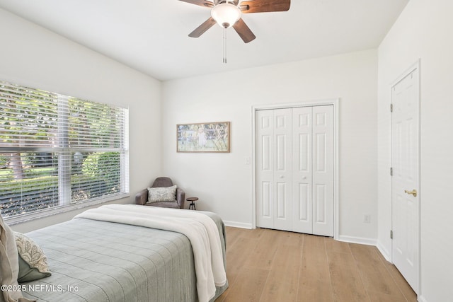 bedroom featuring light wood-style flooring, baseboards, a closet, and a ceiling fan
