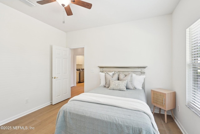 bedroom featuring light wood finished floors, multiple windows, and washer / dryer
