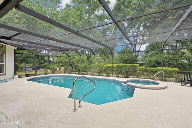 view of swimming pool featuring a patio, a pool with connected hot tub, and view of wooded area