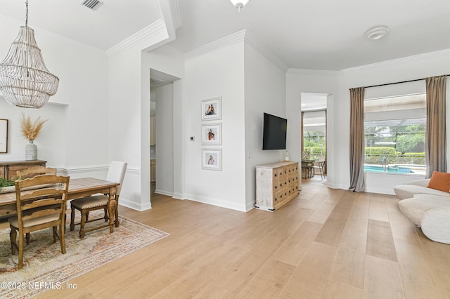 dining room featuring a chandelier, ornamental molding, light wood-style flooring, and baseboards