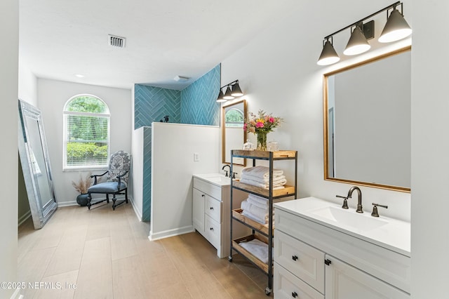 full bathroom featuring two vanities, baseboards, and a shower