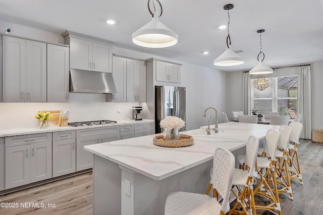 290 Marquesa Cir, Saint Johns, FL 32259 - kitchen featuring appliances with stainless steel finishes, light wood-style floors, gray cabinets, a kitchen bar, and under cabinet range hood