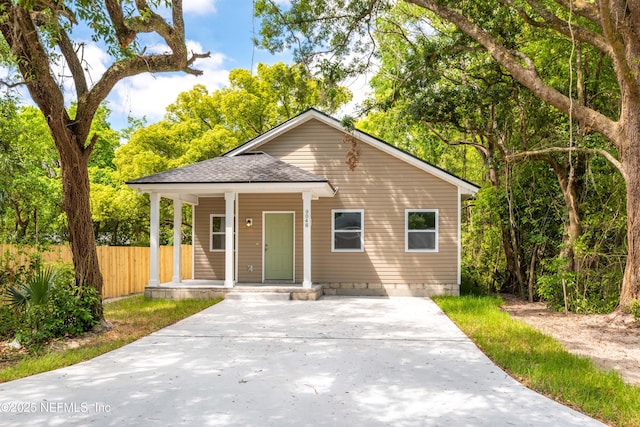 bungalow-style home featuring crawl space, fence, a porch, and roof with shingles
