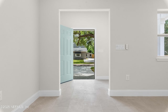entryway with a wealth of natural light, light tile patterned floors, and baseboards
