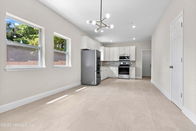 kitchen featuring a chandelier, stainless steel appliances, white cabinetry, and baseboards