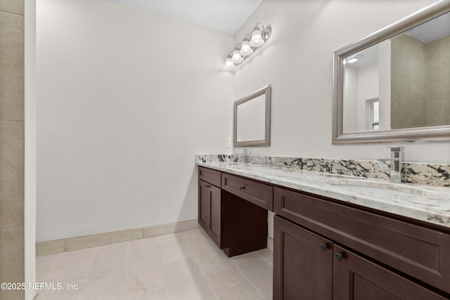 bathroom with baseboards, tile patterned flooring, double vanity, and a sink