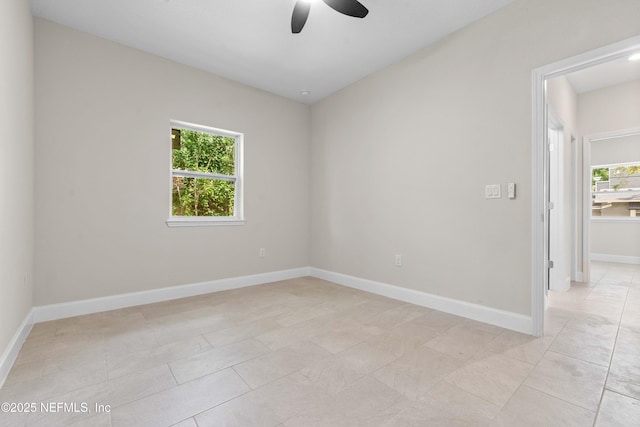 spare room with light tile patterned floors, a ceiling fan, and baseboards