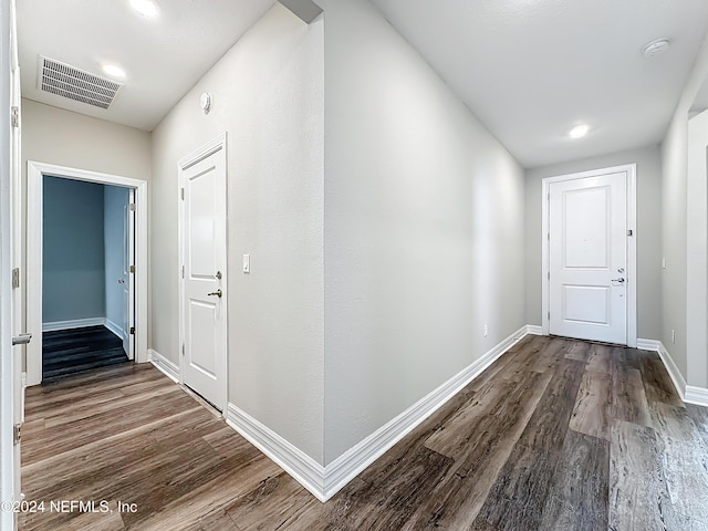 hall with dark wood finished floors, visible vents, and baseboards