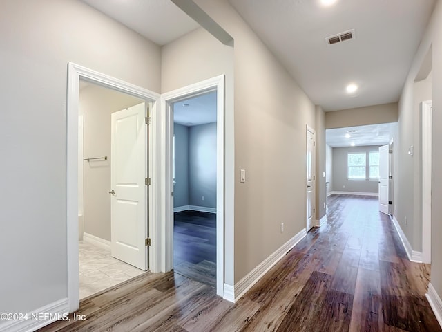 hall with baseboards, visible vents, and wood finished floors